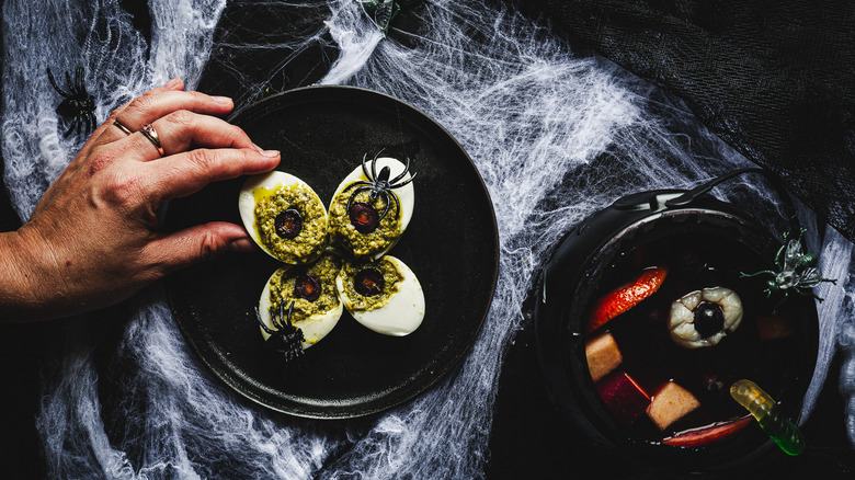 hand picking a deviled egg from a black plate