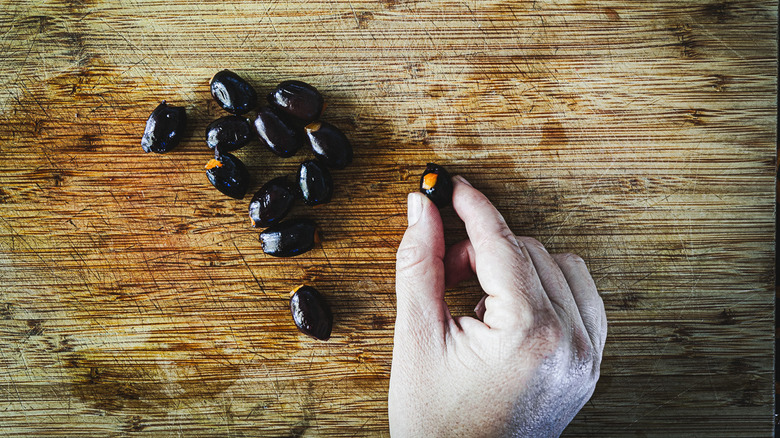 hand holding a black olive stuffed with a bell pepper