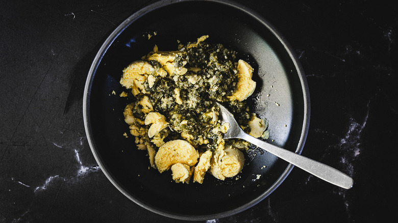 black bowl with egg yolk and pesto with spoon