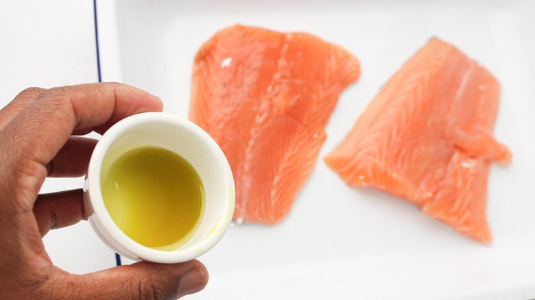 hand pouring oil onto fish