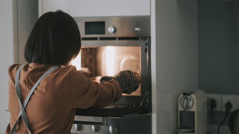 woman pulling cake from oven