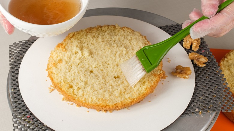 brushing simple syrup onto cake 