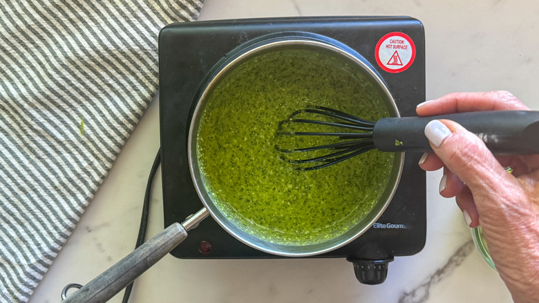 hand stirring pesto and cream