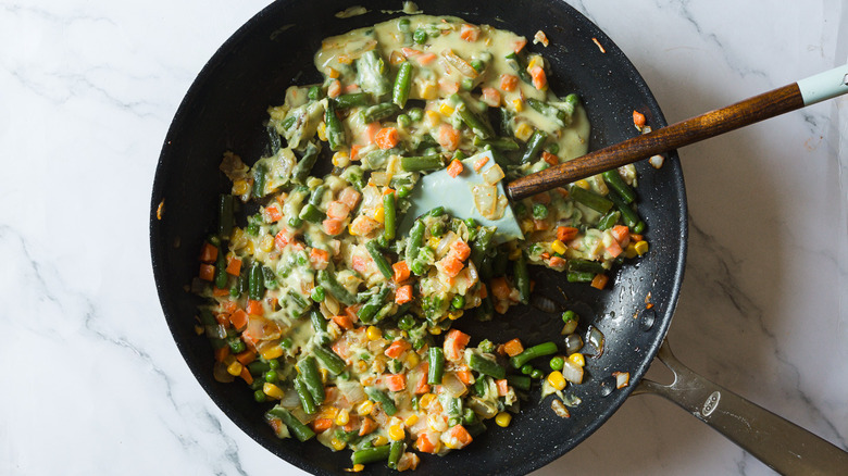 Spatula in pan with veggies in sauce