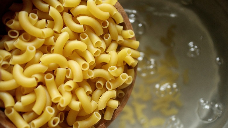 pouring dry pasta into water