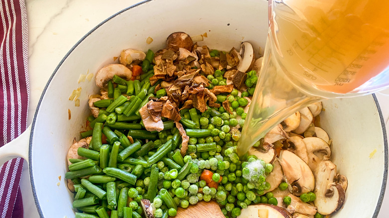 adding broth to pot