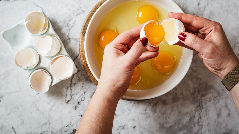 hands breaking eggs into bowl