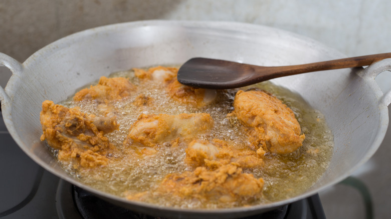 Chicken frying in wok of oil