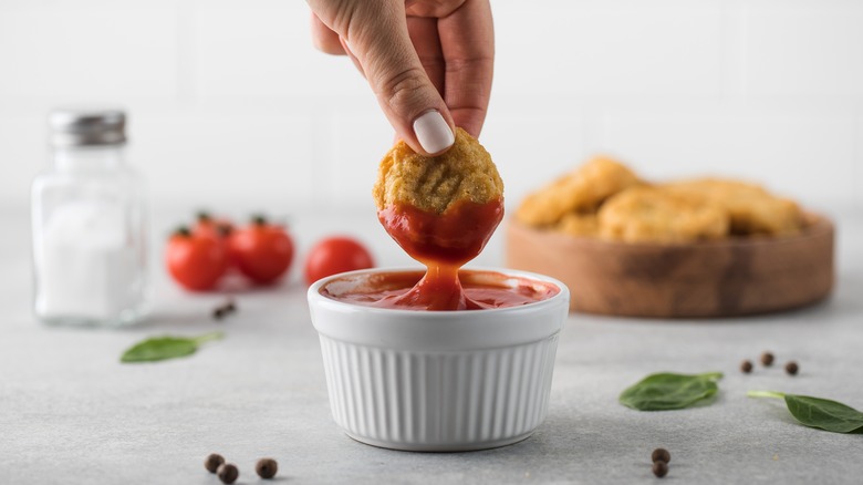 dipping chicken nugget in ketchup