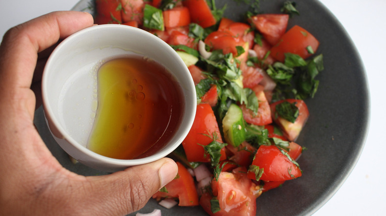 holding dressing over chopped vegetables