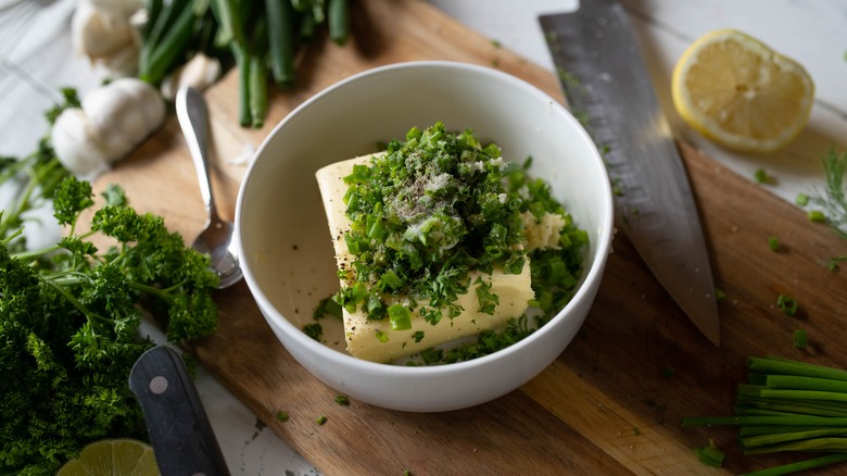 butter and herbs in a bowl on cutting board