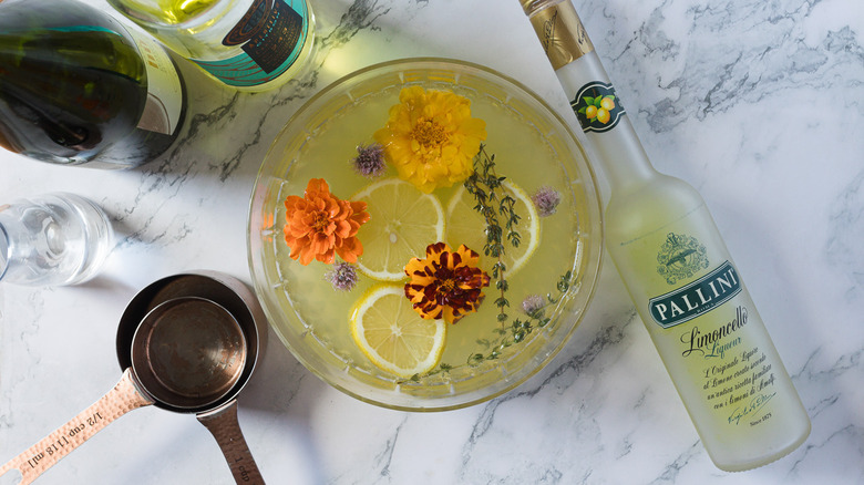 Large bowl of punch with flowers and herbs and other ingredients around