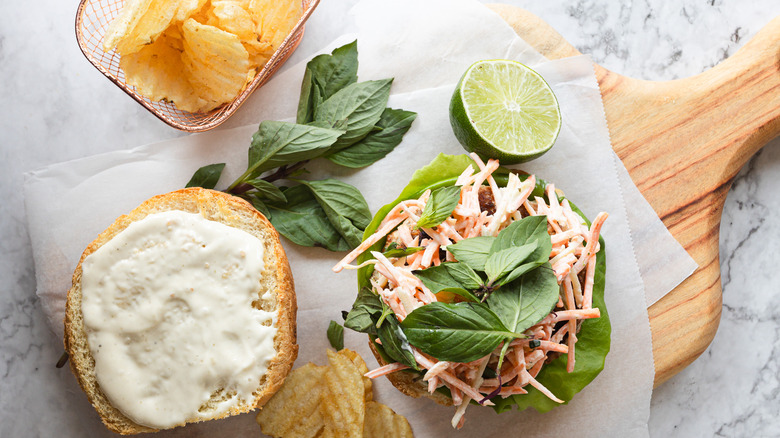 Overhead view of turkey burger with carrot slaw and Thai basil with chips