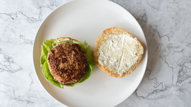 Two bun halves, one with lettuce and burger