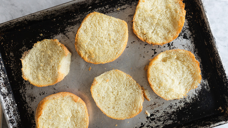 Toasted bun halves on baking sheet