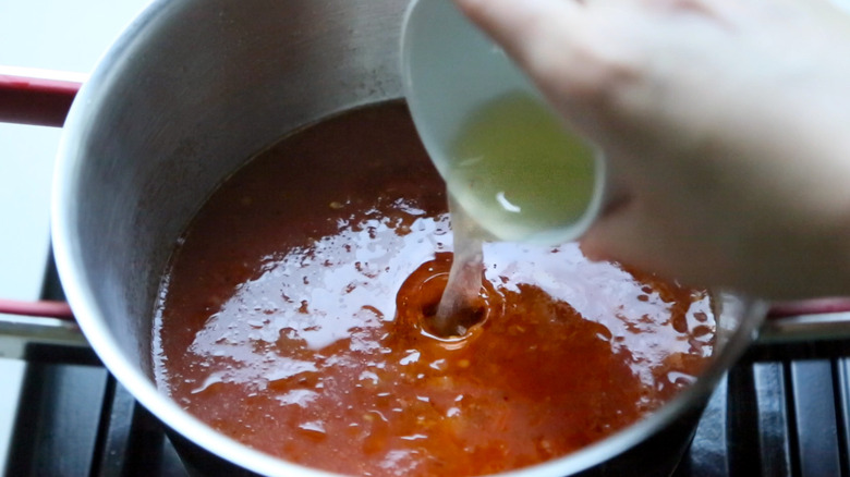 lemon juice pouring into red sauce