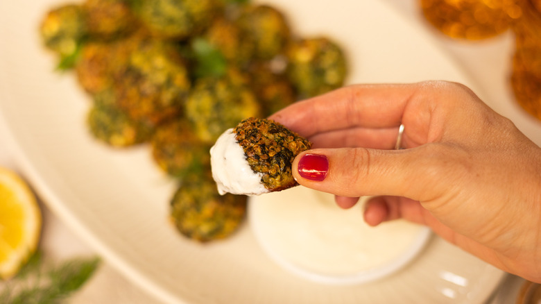 herby spinach quinoa balls dipped in sauce 