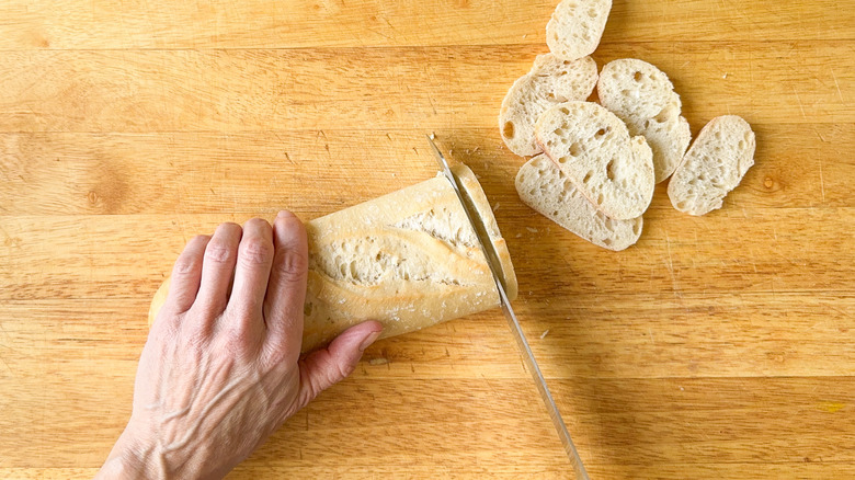 Slicing baguette on cutting board