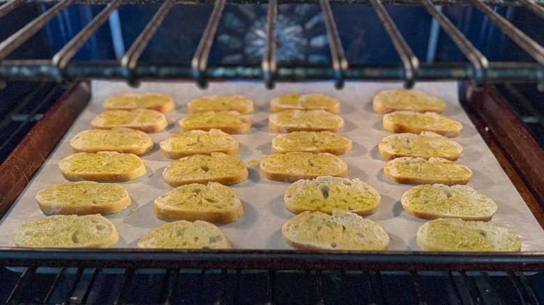 Baguette slices on baking sheet baking in oven