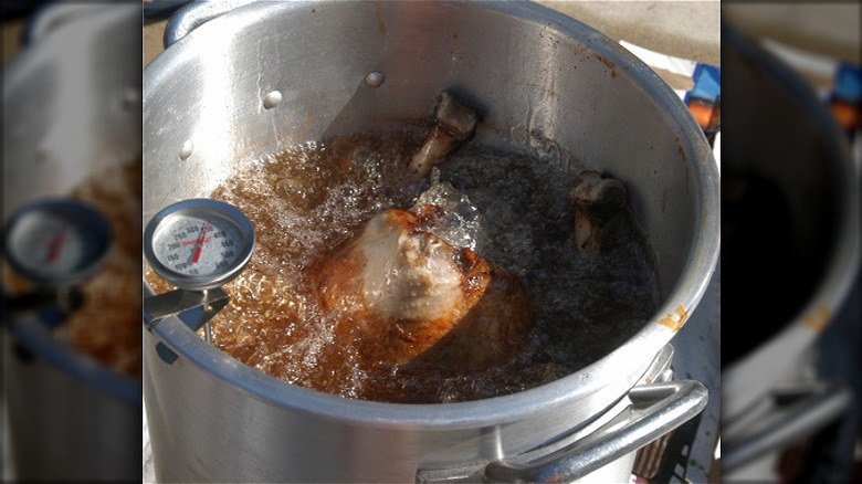 Turkey frying in a large stock pot with a thermometer