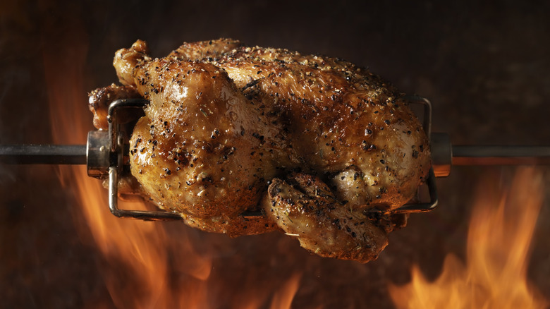 Rotisserie turkey over flames on a grill