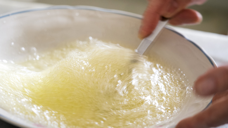 Hands whisking egg whites in a bowl