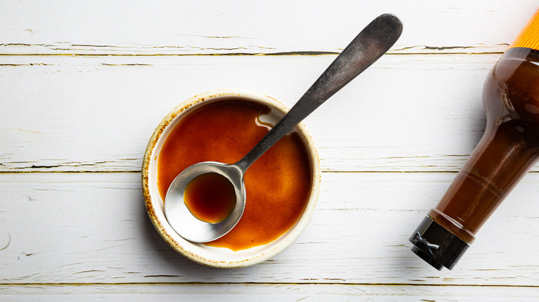 Worcestershire sauce in a bowl with an unbranded bottle at the side
