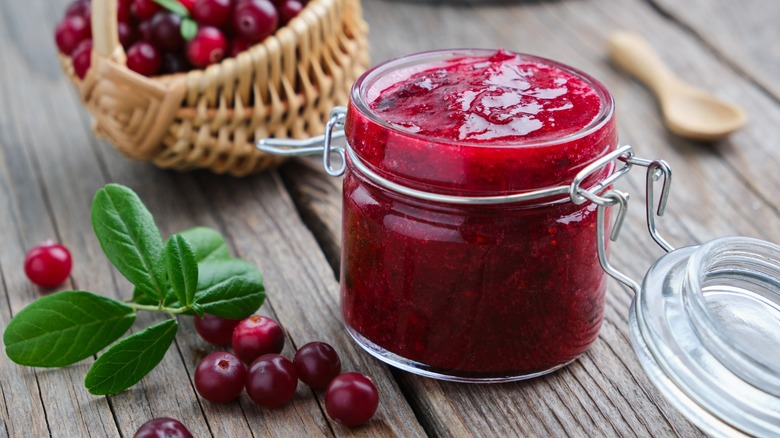 A glass jar of cranberry sauce with cranberries