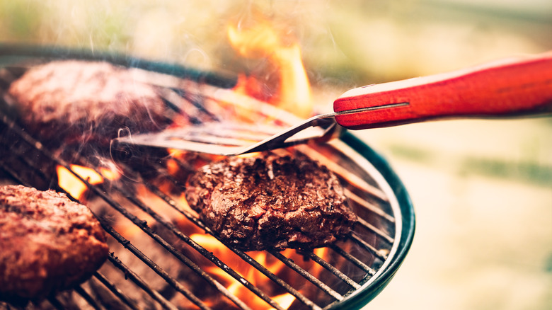 hamburgers on grill with spatula