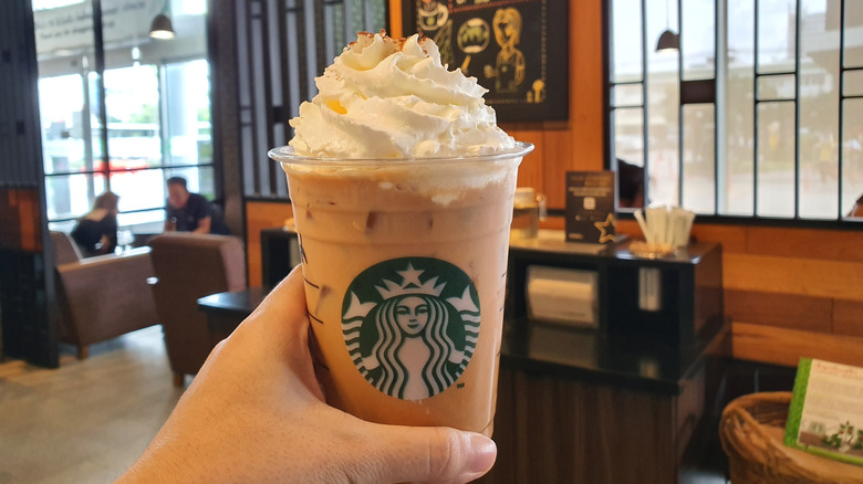 A person holding a pumpkin spice latte.