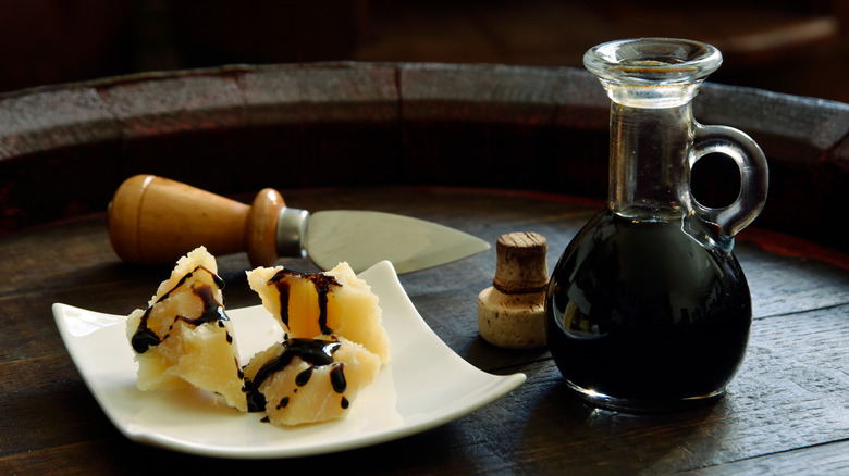 balsamic vinegar in a glass dispenser with parmesan cheese on a barrel