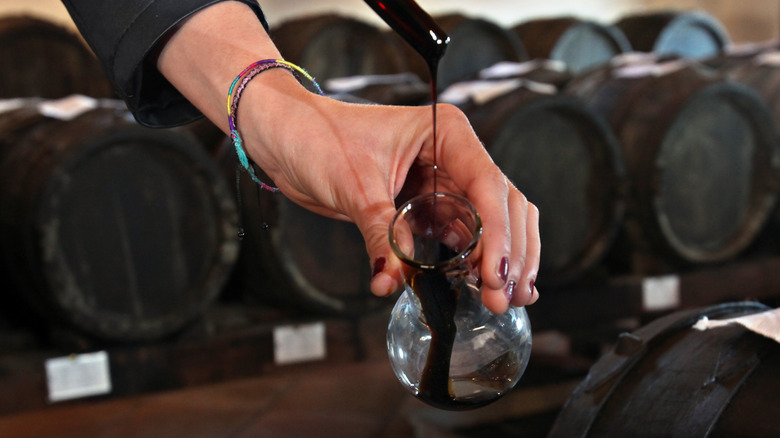 pouring balsamic vinegar with barrels in background