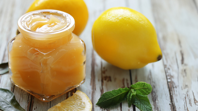 Open jar of lemon curd with a lemon