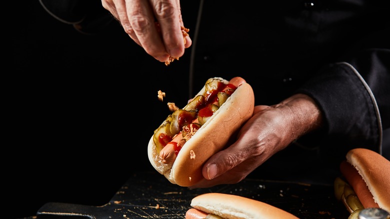 chef garnishing a hot dog