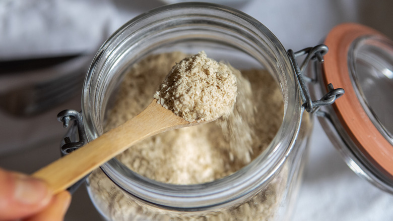 Open jar of yeast with a spoonful of yeast