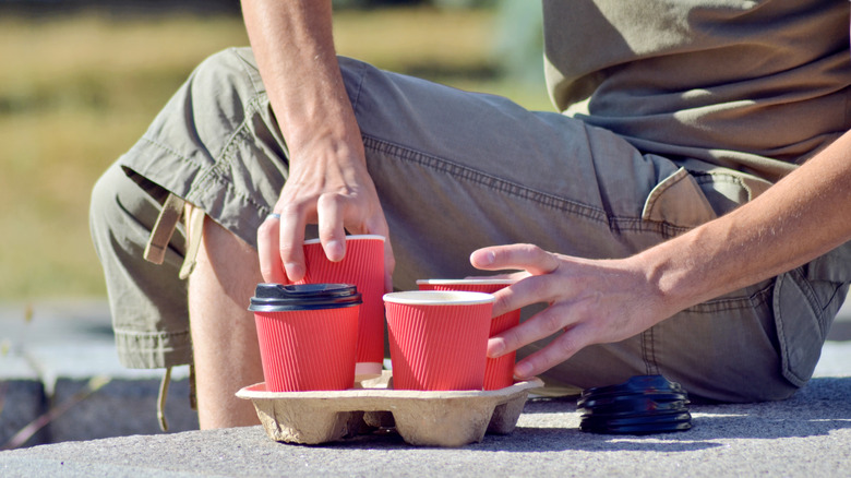 Man removing coffee cup lids