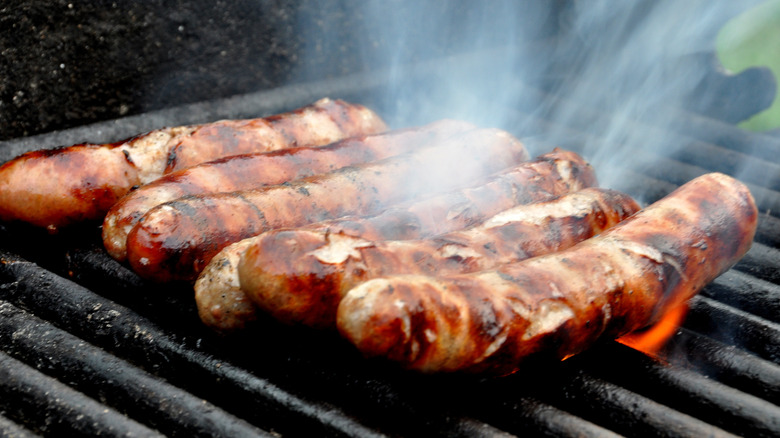 Six bratwurst cooking on grill