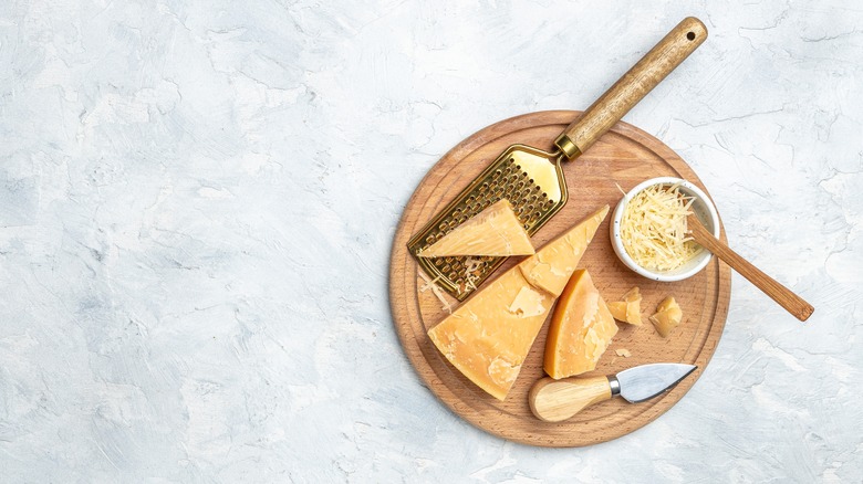 Grated and whole parmesan cheese on a board