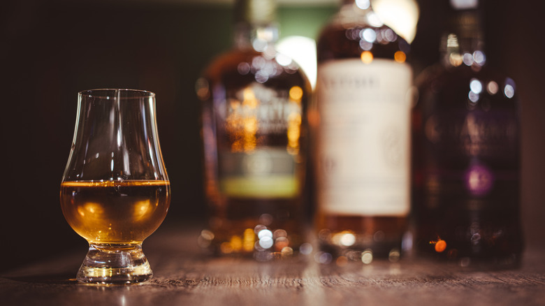 bourbon in a glencairn glass with bottles in the background