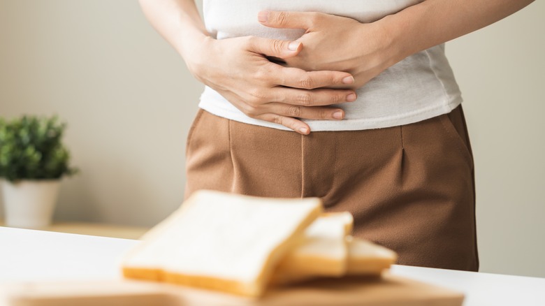 woman holding stomach near bread