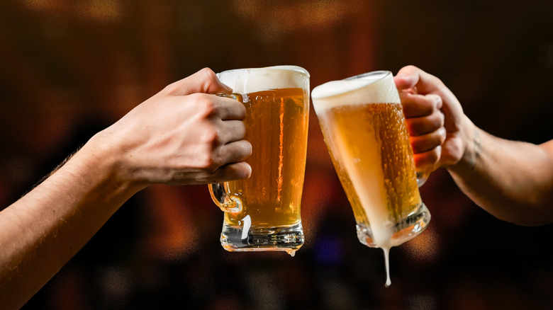 two people toasting with glasses of beer