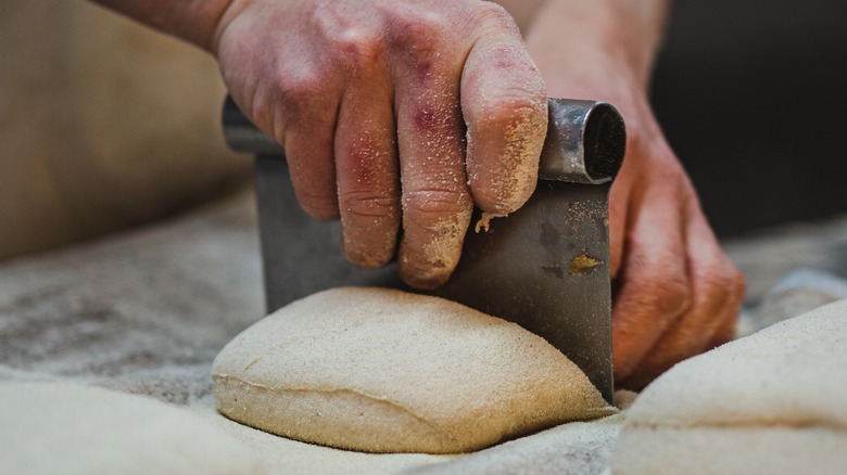 Hand cutting bread dough with cleaver