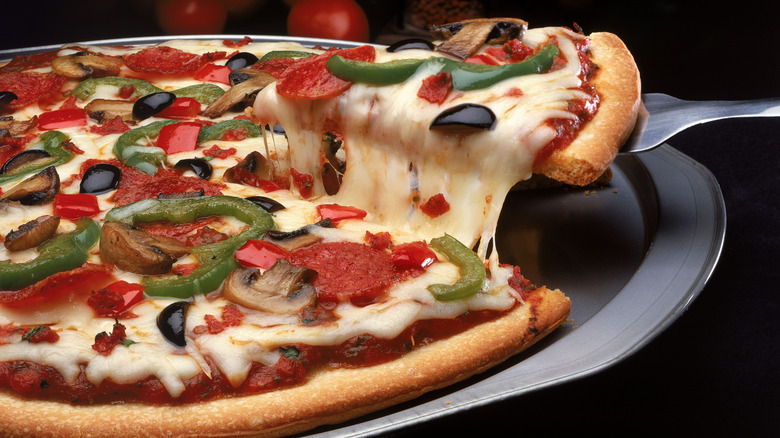 A slice of pizza is pulled up from a pan with a spatula