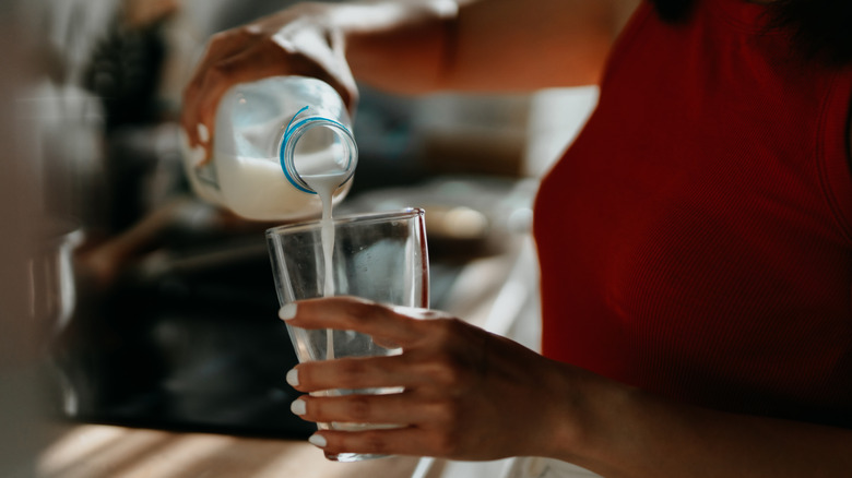 person pouring a glass of milk