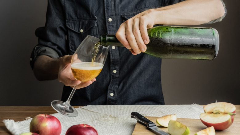 Person pouring cider into wine glass