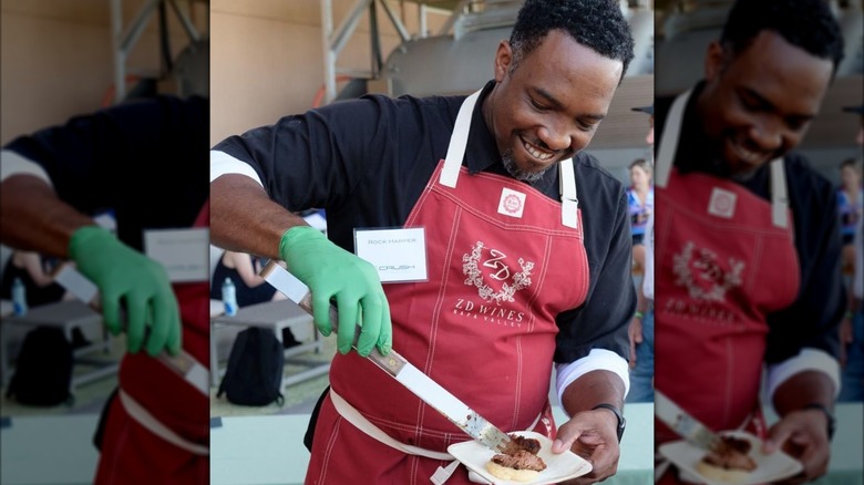 Rock Harper with red apron serving food outside