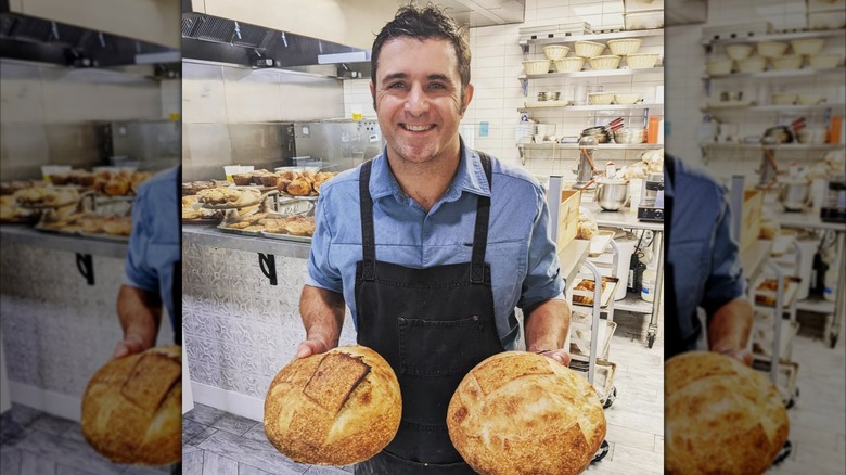 Scott Commings holding two loaves of bread in a bakery