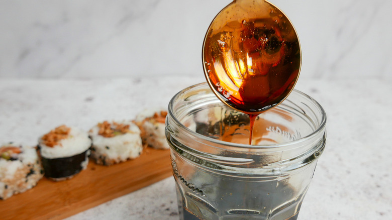 Eel sauce on spoon dripping into jam jar