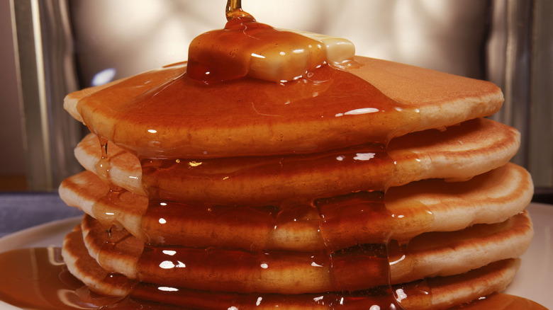 pouring maple syrup on pancakes