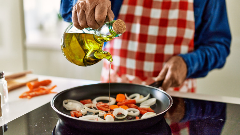 pouring oil in skillet with vegetables